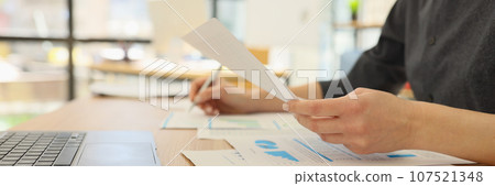 Woman analyzes papers with diagrams and statistics in office 107521348
