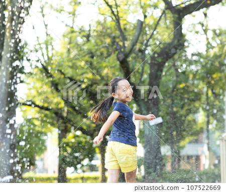 Girl enjoying water play in the park Girl enjoying water play in the park 107522669