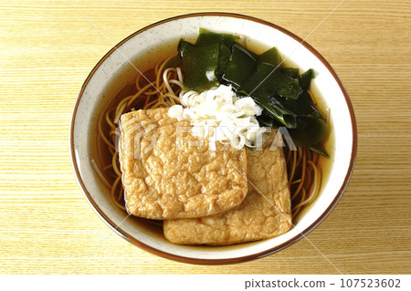 頭頂上的狐狸蕎麥麵,上面放著兩片炸豆腐、海藻和蔥。 頭頂上的狐狸蕎麥麵,上面放著兩片炸豆腐、海藻和蔥。 107523602