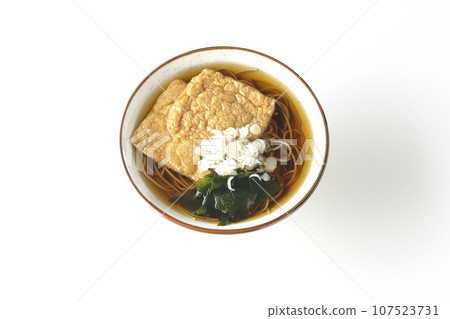 白色背景下,頭頂上的狐狸蕎麥麵,上面放著兩塊炸豆腐、海藻和大蔥 白色背景下,頭頂上的狐狸蕎麥麵,上面放著兩塊炸豆腐、海藻和大蔥 107523731