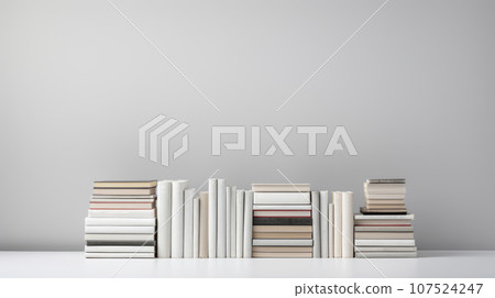 A stack of books on a white wall. This image shows a pile of books of different sizes and colors stacked in a random manner on a white background. The books are mostly white or light-colored, creating 107524247