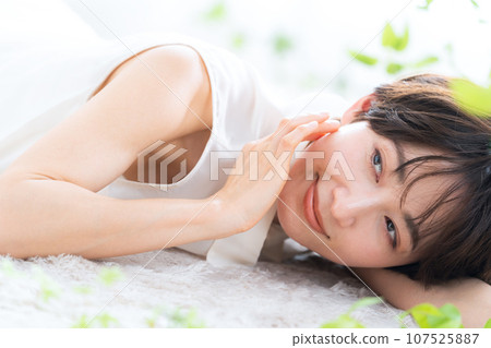 A middle-aged woman lying down in the living room and doing skin care 107525887