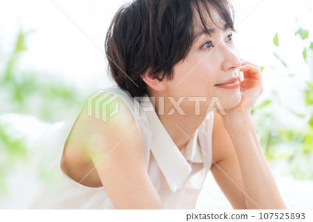 A middle-aged woman lying down in the living room and doing skin care 107525893