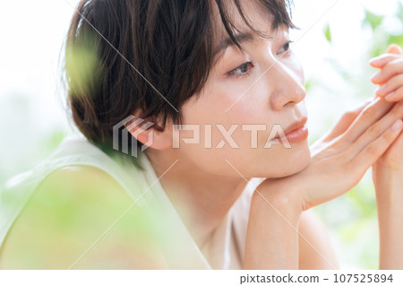 A middle-aged woman lying down in the living room and doing skin care 107525894