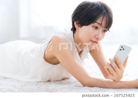 中年婦女躺在客廳看著她的智慧型手機 107525925