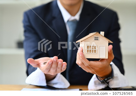 Male realtor or bank worker holding house model and keys. Real estate, loan and property investment concept 107526565