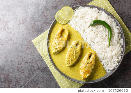 Bengali Shorshe Ilish or Hilsa cooked in Mustard Gravy served with white rice closeup on the plate. Horizontal top view 107526610