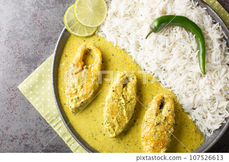 Hilsa fish in Mustard Sauce or shorshe Ilish served with white rice closeup on the plate. Horizontal top view 107526613