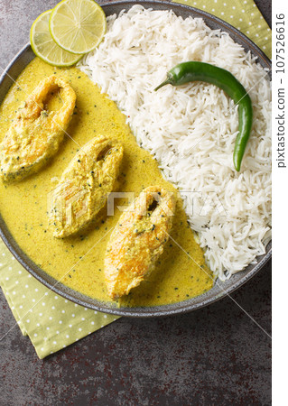 Hilsa fish cooked with mustard and traditional Bangladeshi spices served with white rice closeup on the plate. Vertical top view 107526616