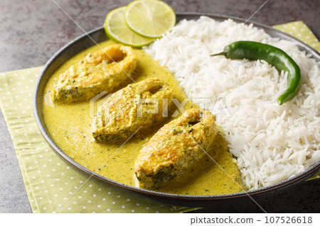 Bengali Shorshe Ilish or Hilsa cooked in Mustard Gravy served with white rice closeup on the plate. Horizontal 107526618