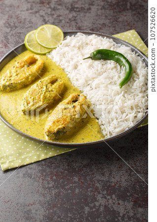 Hilsa fish cooked with mustard and traditional Bangladeshi spices served with white rice closeup on the plate. Vertical 107526620