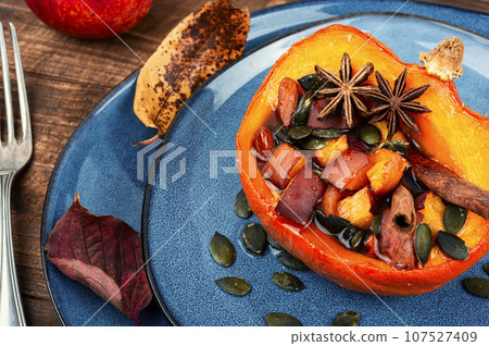 Baked half of pumpkin with fruits and spices. 107527409