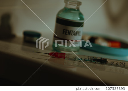 syringe and vial of fentanyl in a sordid bathroom 107527893