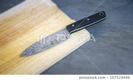 Damascus steel knife on a wooden board 107528498