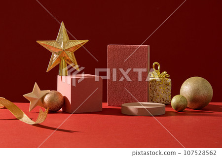 Background for the presentation of cosmetic products with Christmas concept. Front view of empty podiums decorated with cute yellow decorative accessory on red background Background for the presentation of cosmetic products with Christmas concept. Front view of empty podiums decorated with cute yellow decorative accessory on red background 107528562