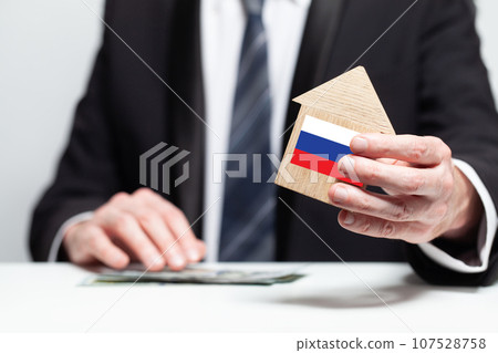 Businessman hand holding wooden home model with Russian flag. insurance and property concepts 107528758