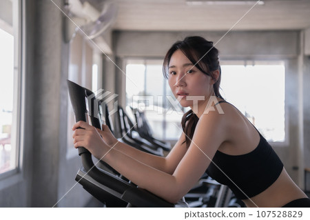 Asian woman exercising with exercise equipment in the gym. Asian woman exercising with exercise equipment in the gym. 107528829