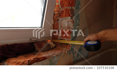 taking measurements from the window opening after installing the window using a tape measure, measuring the width and depth of the opening for further installation of slopes taking measurements from the window opening after installing the window using a tape measure, measuring the width and depth of the opening for further installation of slopes 107530106