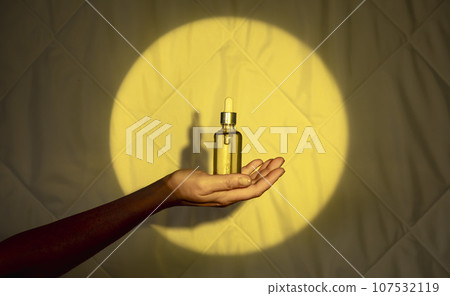 woman's hand on the background of a quilt in the yellow light of moon with a dropper with sleeping oil. Fighting insomnia 107532119