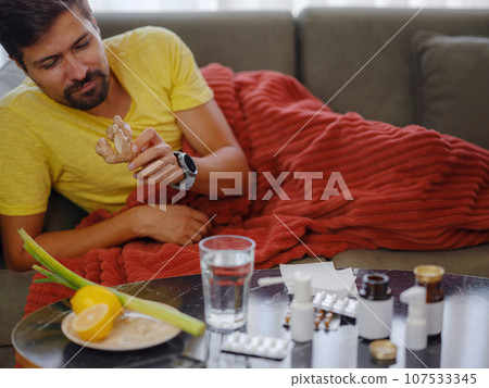Sick man at home. Health care concept. choosing between evidence-based medicine and traditional medicine. pharmacological tablets against lemon, ginger and onion 107533345