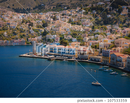 Symi Island, Greece. Greece islands holidays from Rhodos in Aegean Sea. Colorful neoclassical houses in bay of Symi. Holiday travel background. view from hill 107533359