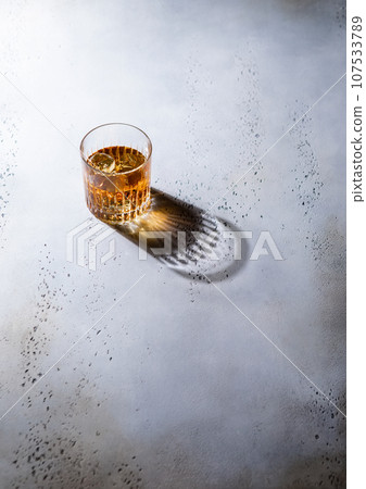 Whiskey in crystal glass with ice cubes and black shadow.Top view. 107533789