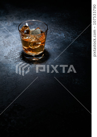 Whiskey glass with ice cubes in middle of black background. Top view. 107533790