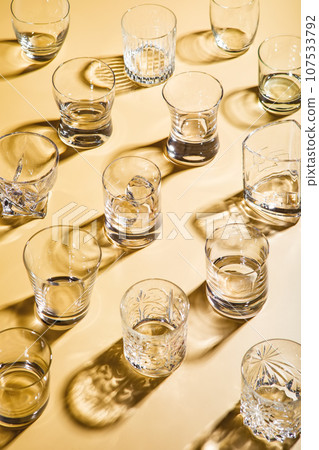 Various empty whiskey glasses on golden background. Various empty whiskey glasses on golden background. 107533792