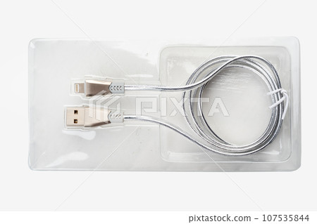 Silver-colored USB cable in plastic packaging on a white background. Silver-colored USB cable in plastic packaging on a white background. 107535844