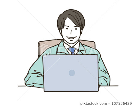 A man wearing work clothes looking at the camera while working on a computer 107536429