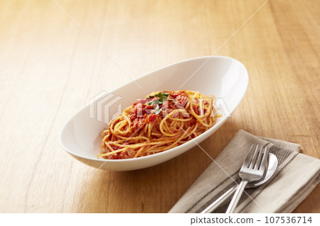 Tuna tomato pasta on wooden table, white plate 107536714