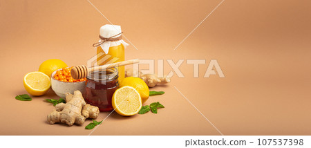 Composition with detox drink, sea buckthorn berries, lemons, mint, ginger, honey in glass jar. Food for immunity stimulation and against flu. Healthy natural remedies to boost immune system 107537398