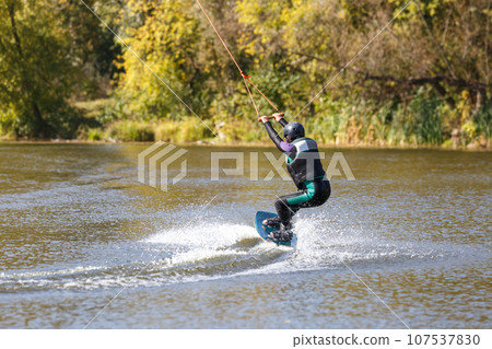 A woman surfing on wakeboard along the river 107537830