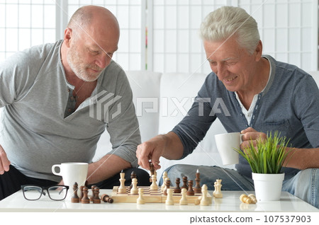 two old senior men playing chess at home two old senior men playing chess at home 107537903