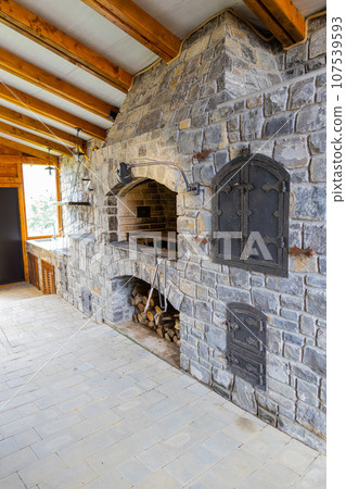 Stone restaurant barbecue firewood, open brick oven cooking food dishes on fire indoors in backyard 107539593