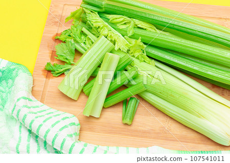 Fresh Celery Stem and Chopped Celery Sticks on Wooden Cutting Board Fresh Celery Stem and Chopped Celery Sticks on Wooden Cutting Board 107541011
