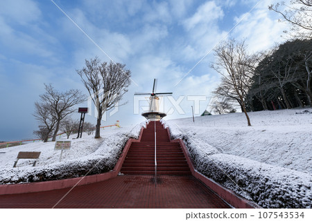 Dutch windmill on the snow-covered hill of Naganuma Hootopia Park 107543534