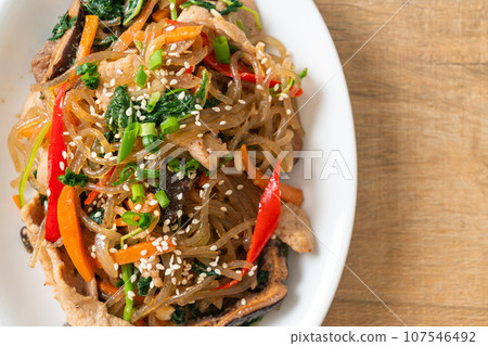 japchae or stir-fried Korean vermicelli noodles with vegetables and pork topped with white sesame 107546492