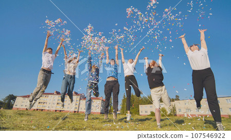 Friends toss colorful paper confetti from their hands. 107546922