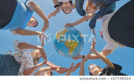 Young boys surround the globe of the world with their palms. Young boys surround the globe of the world with their palms. 107546928