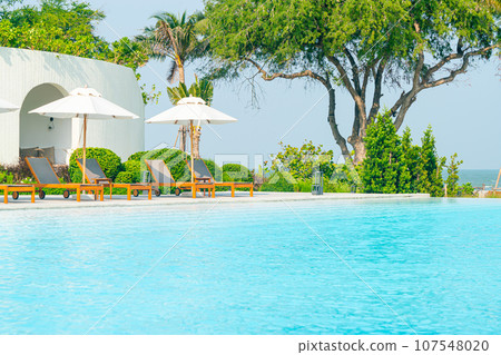 umbrella with bed pool around swimming pool with ocean sea background umbrella with bed pool around swimming pool with ocean sea background 107548020