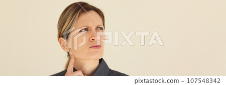 Pensive woman touches chin with finger looking to side Pensive woman touches chin with finger looking to side 107548342