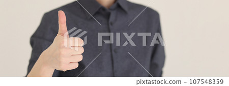 Woman shows thumb up gesture standing on beige background Woman shows thumb up gesture standing on beige background 107548359