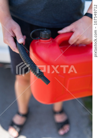 Stop for refueling, no refueling, problems with fuel. A man holds a red canister near his car, close-up. 107549712