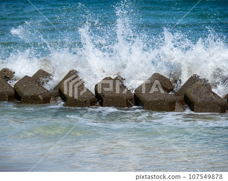 Waves crash against the wave-dissipating blocks on the coast, creating wave spray. Waves crash against the wave-dissipating blocks on the coast, creating wave spray. 107549878