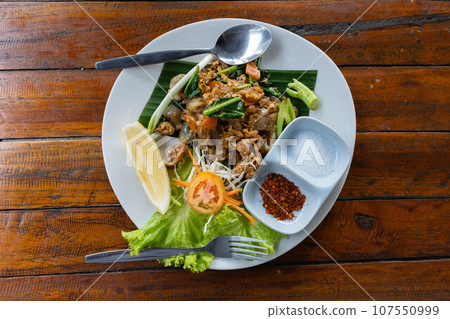 Stir-fried rice noodles with black soy sauce, pork and kale. Thai food (Pad See Ew) 107550999