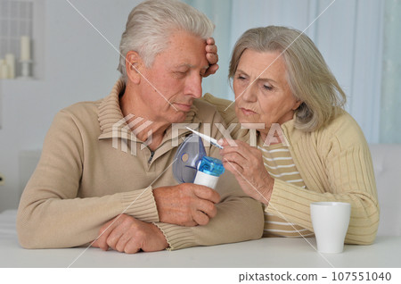 elderly couple at the table treating an illness at home 107551040