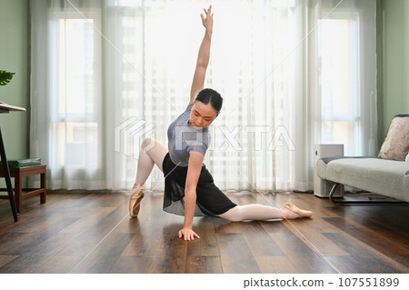 Beautiful woman in pointe shoes practicing ballet at home. People, dance and art concept Beautiful woman in pointe shoes practicing ballet at home. People, dance and art concept 107551899