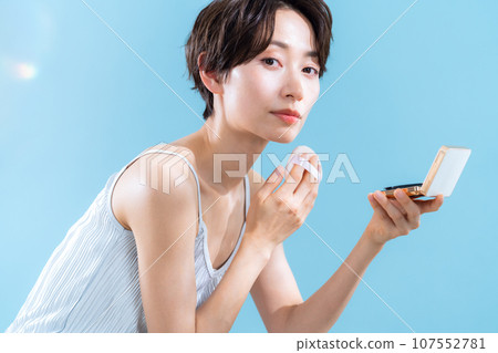 A middle-aged woman taking UV care against a blue background A middle-aged woman taking UV care against a blue background 107552781