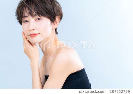 A middle-aged woman doing skin care against a gray background 107552799